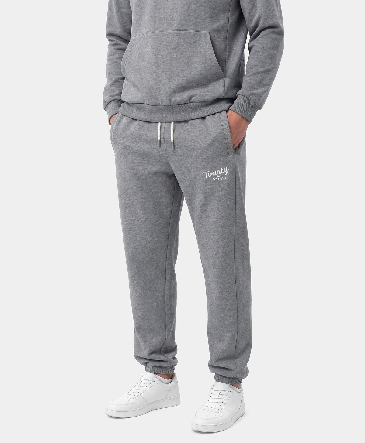 A person wearing Flecking Gray Toasty Heated Sweatpants with white sneakers and a gray sweatshirt